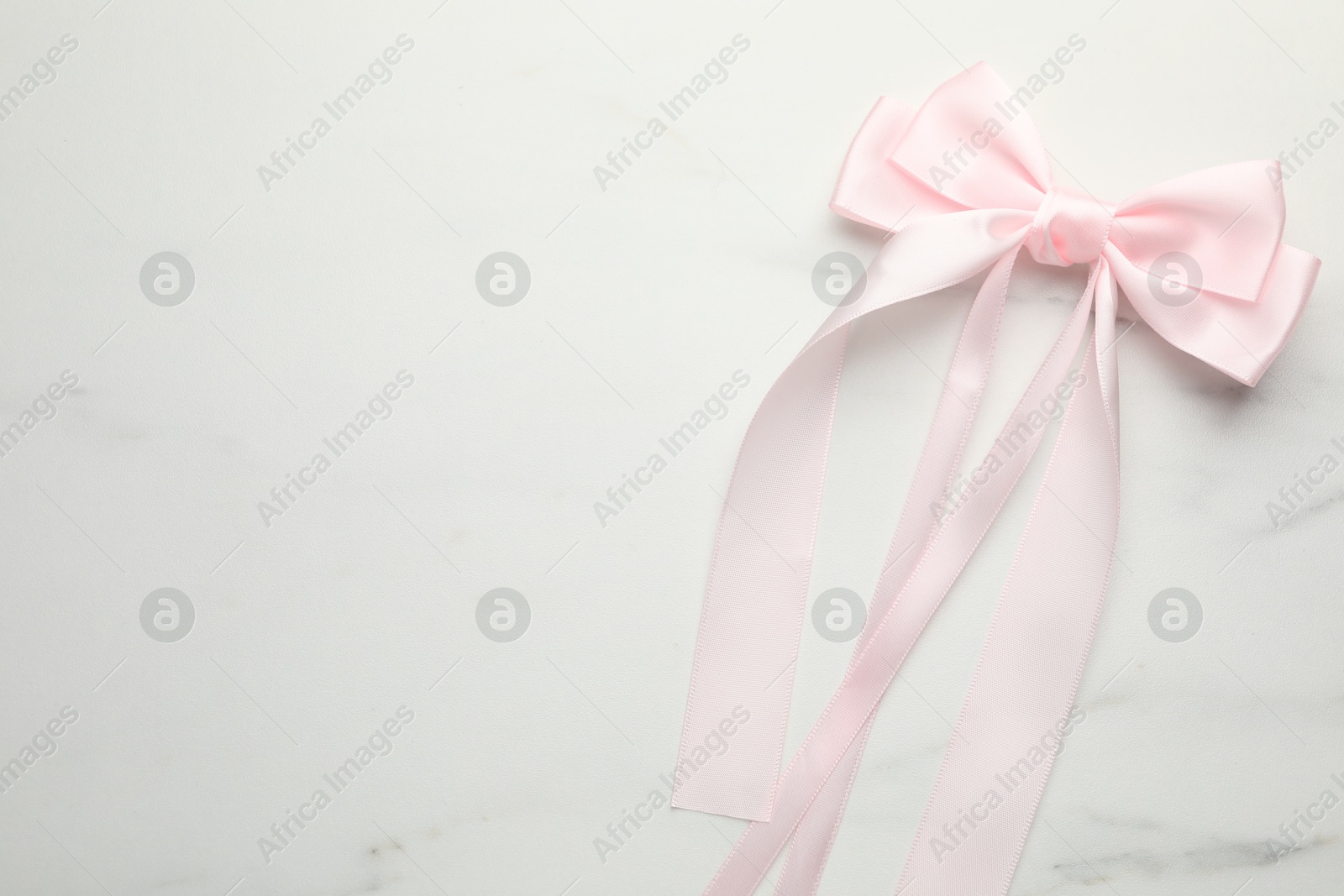 Photo of Beautiful hair bow on white marble table, top view. Space for text