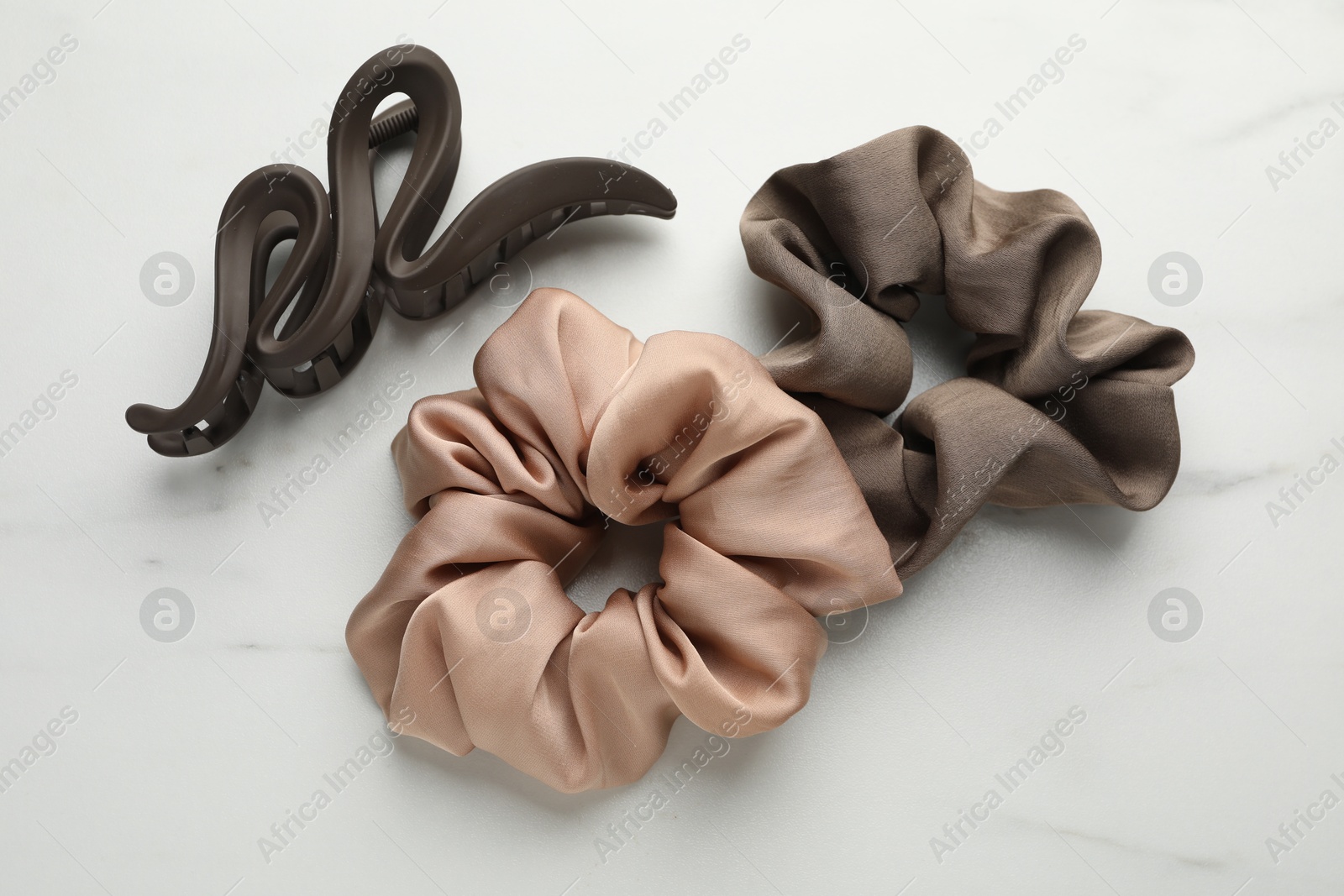 Photo of Different hair accessories on white marble table, flat lay