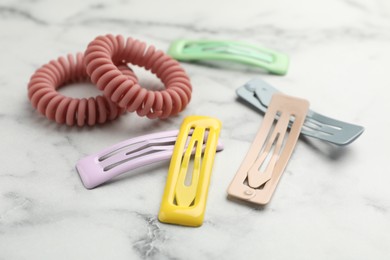 Photo of Different hair accessories on white marble table, closeup