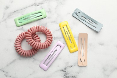 Different hair accessories on white marble table, flat lay