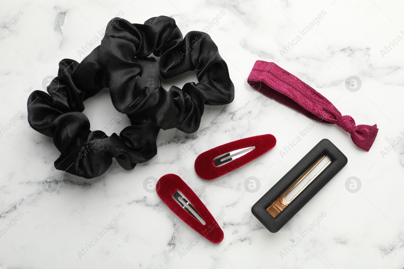 Photo of Different hair accessories on white marble table, flat lay