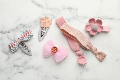 Different hair accessories on white marble table, flat lay