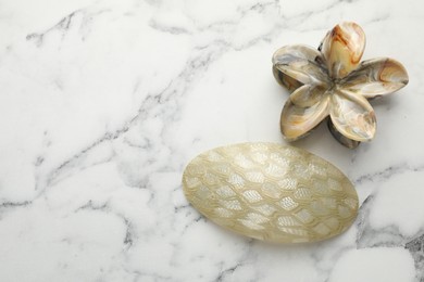 Beautiful hair accessories on white marble table, flat lay. Space for text