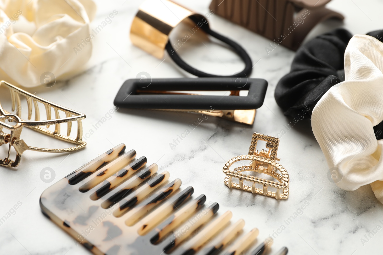 Photo of Different hair accessories on white marble table, closeup