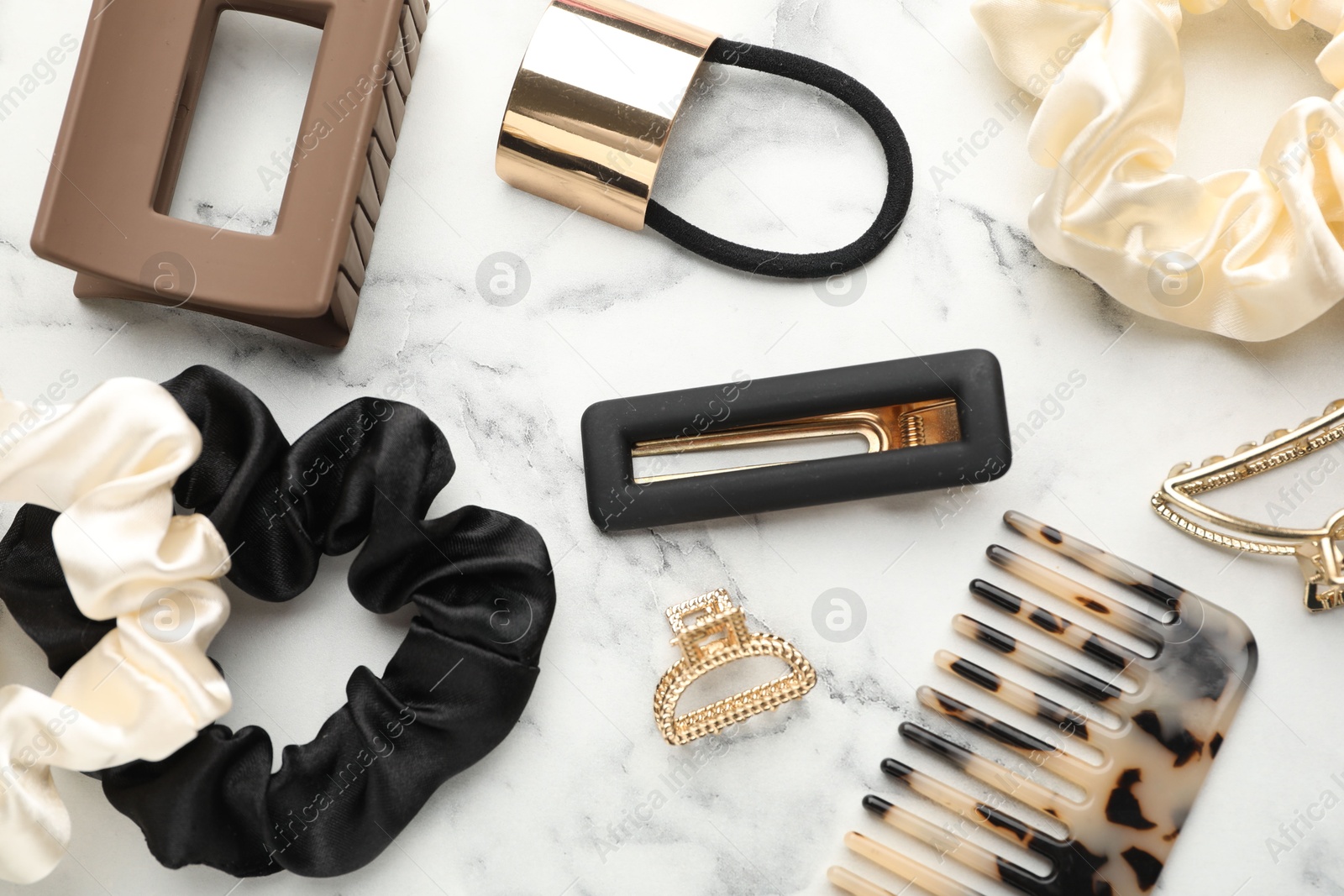 Photo of Different hair accessories on white marble table, flat lay