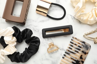 Different hair accessories on white marble table, flat lay