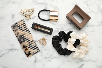 Different hair accessories on white marble table, flat lay