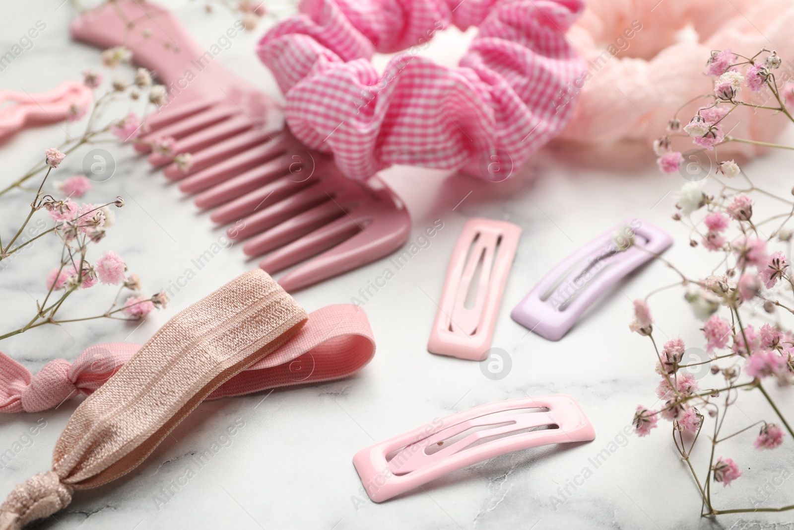 Photo of Different hair accessories and gypsophila flowers on white marble table, closeup