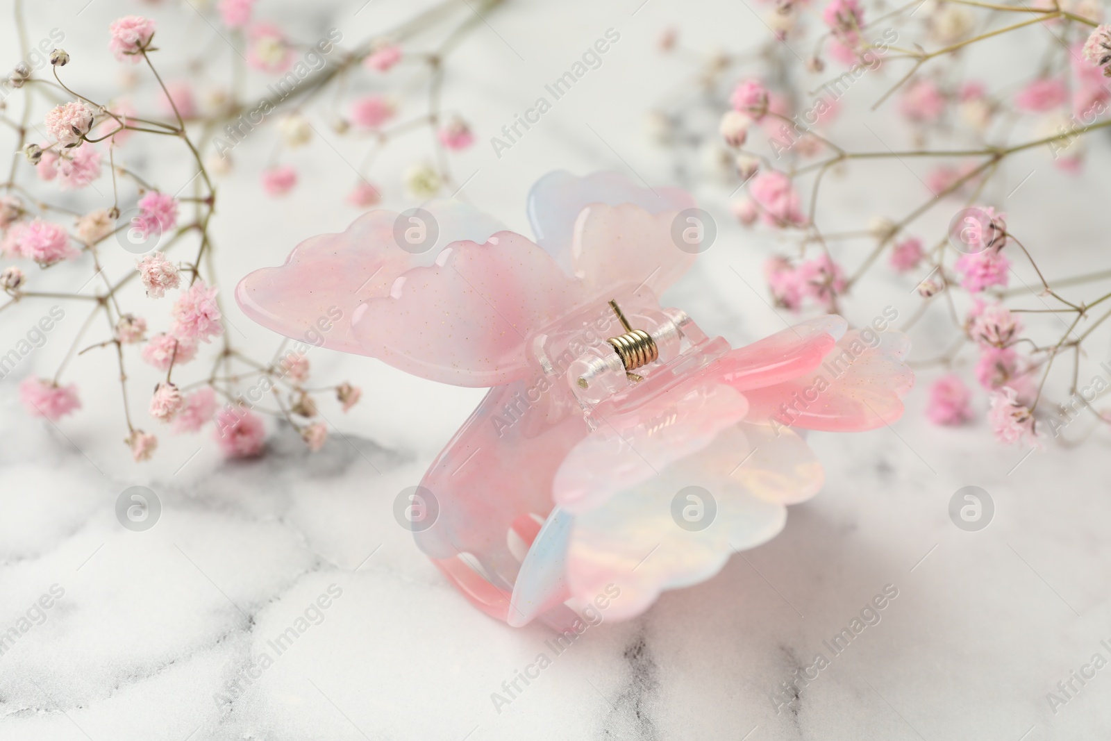 Photo of Different hair clip and gypsophila flowers on white marble table, closeup