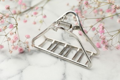 Photo of Different hair clip and gypsophila flowers on white marble table, closeup