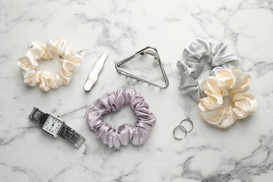 Different hair accessories and wrist watch on white marble table, flat lay