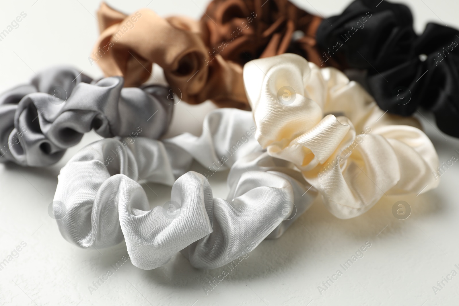 Photo of Different hair scrunchies on white table, closeup