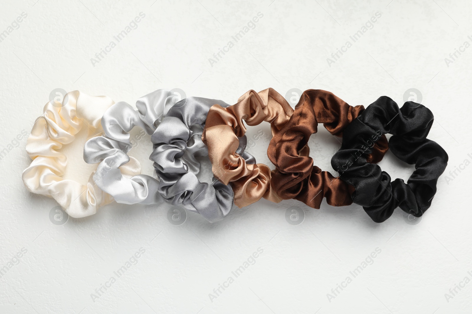 Photo of Different hair scrunchies on white table, flat lay