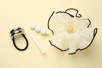 Different hair accessories on beige background, flat lay