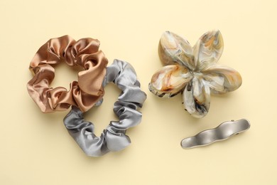 Different hair accessories on beige background, flat lay