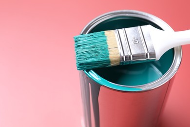 Photo of Can of teal paint and brush on color background, closeup. Space for text