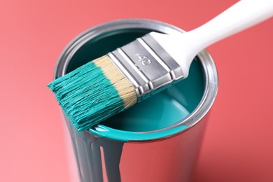 Photo of Can of teal paint and brush on color background, closeup