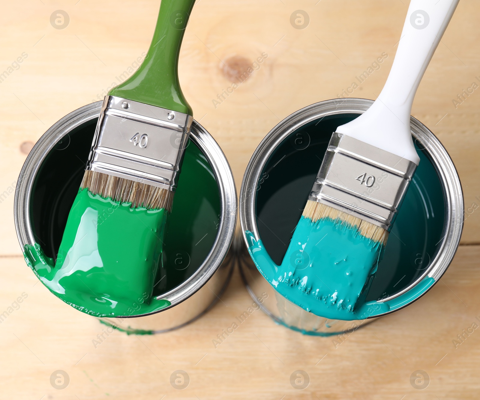 Photo of Cans of paint and brushes on wooden table, top view