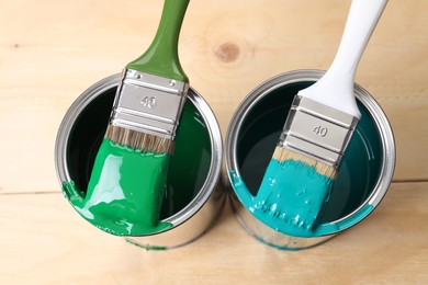 Photo of Cans of paint and brushes on wooden table, top view