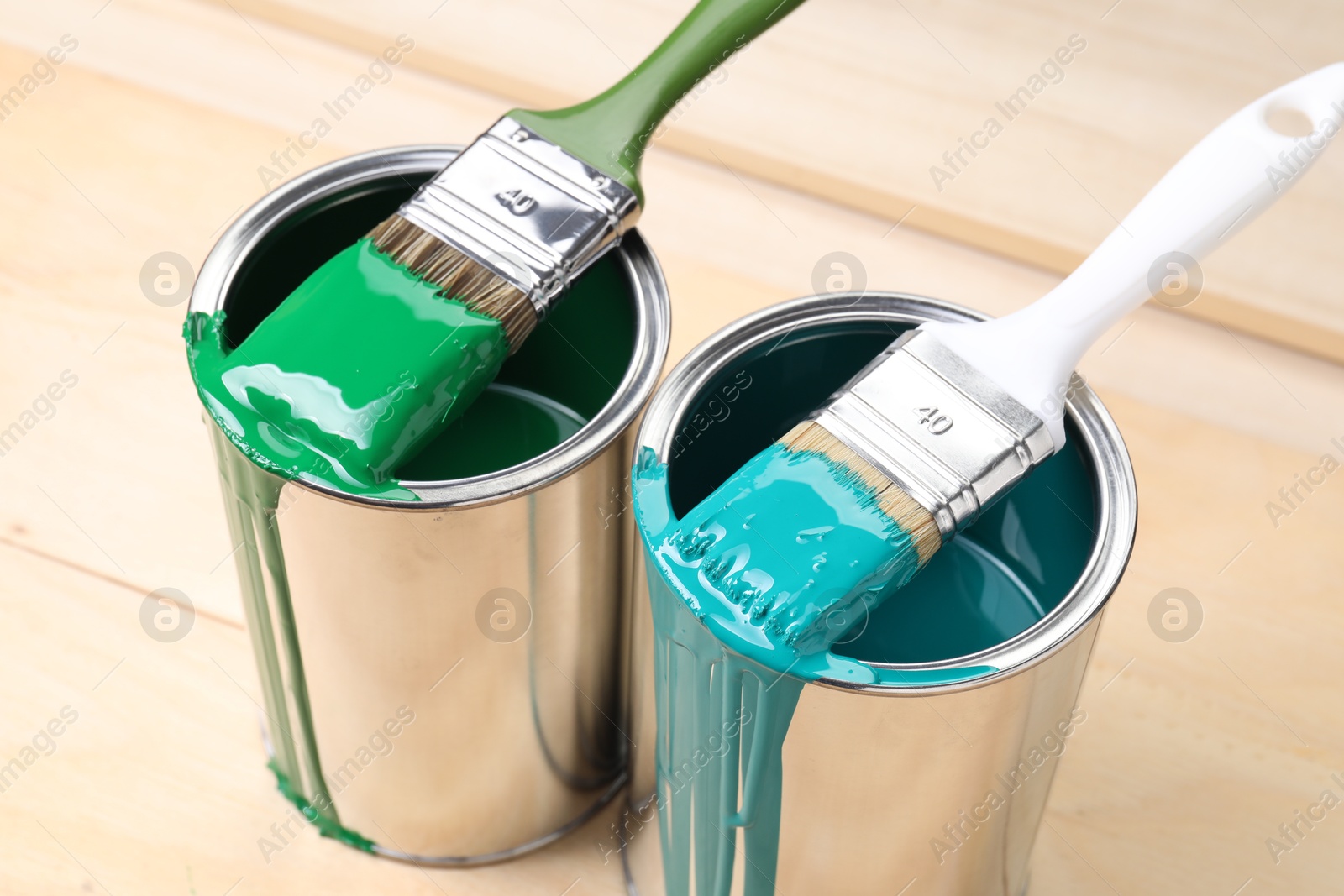 Photo of Cans of paint and brushes on wooden table, closeup