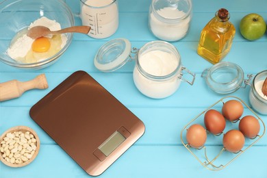 Photo of Electronic kitchen scale and different food products on light blue wooden table indoors, above view