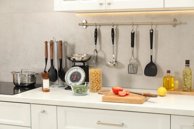 Photo of Retro mechanical kitchen scale, other utensils and different food products on white marble countertop indoors