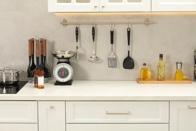 Photo of Retro mechanical kitchen scale, other utensils and spices on white marble table indoors