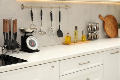 Photo of Retro mechanical kitchen scale, other utensils and spices on white marble table indoors