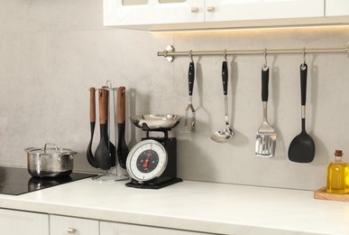 Photo of Retro mechanical kitchen scale on white marble table and other utensils indoors