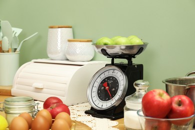 Photo of Kitchen scale, products and cooking utensils on wooden table