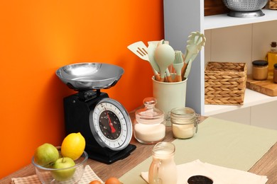 Photo of Kitchen scale, products and cooking utensils on wooden table