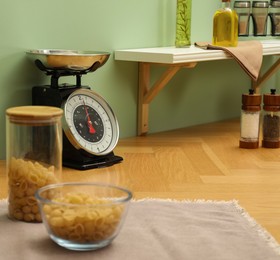 Photo of Kitchen scale, products and cooking utensils on wooden table