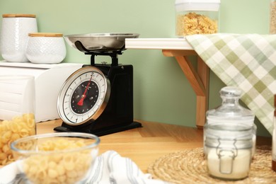 Kitchen scale, products and cooking utensils on wooden table