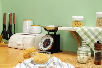 Kitchen scale, products and cooking utensils on wooden table