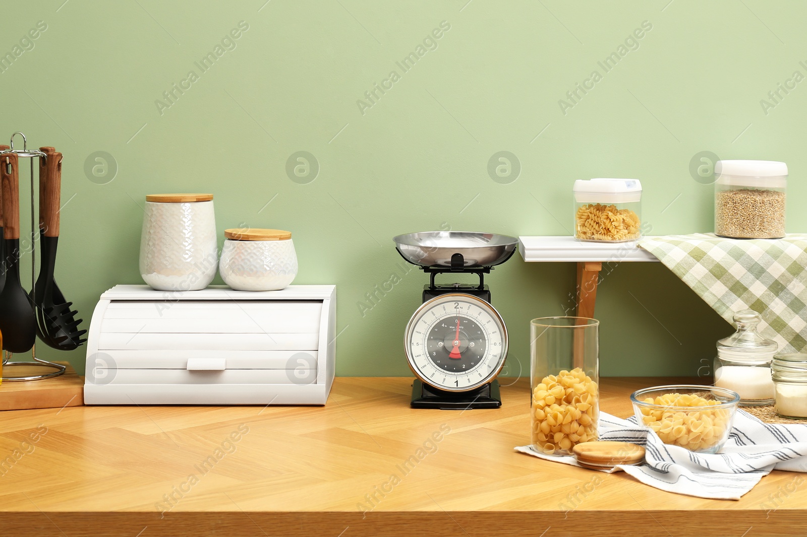 Photo of Kitchen scale, products and cooking utensils on wooden table