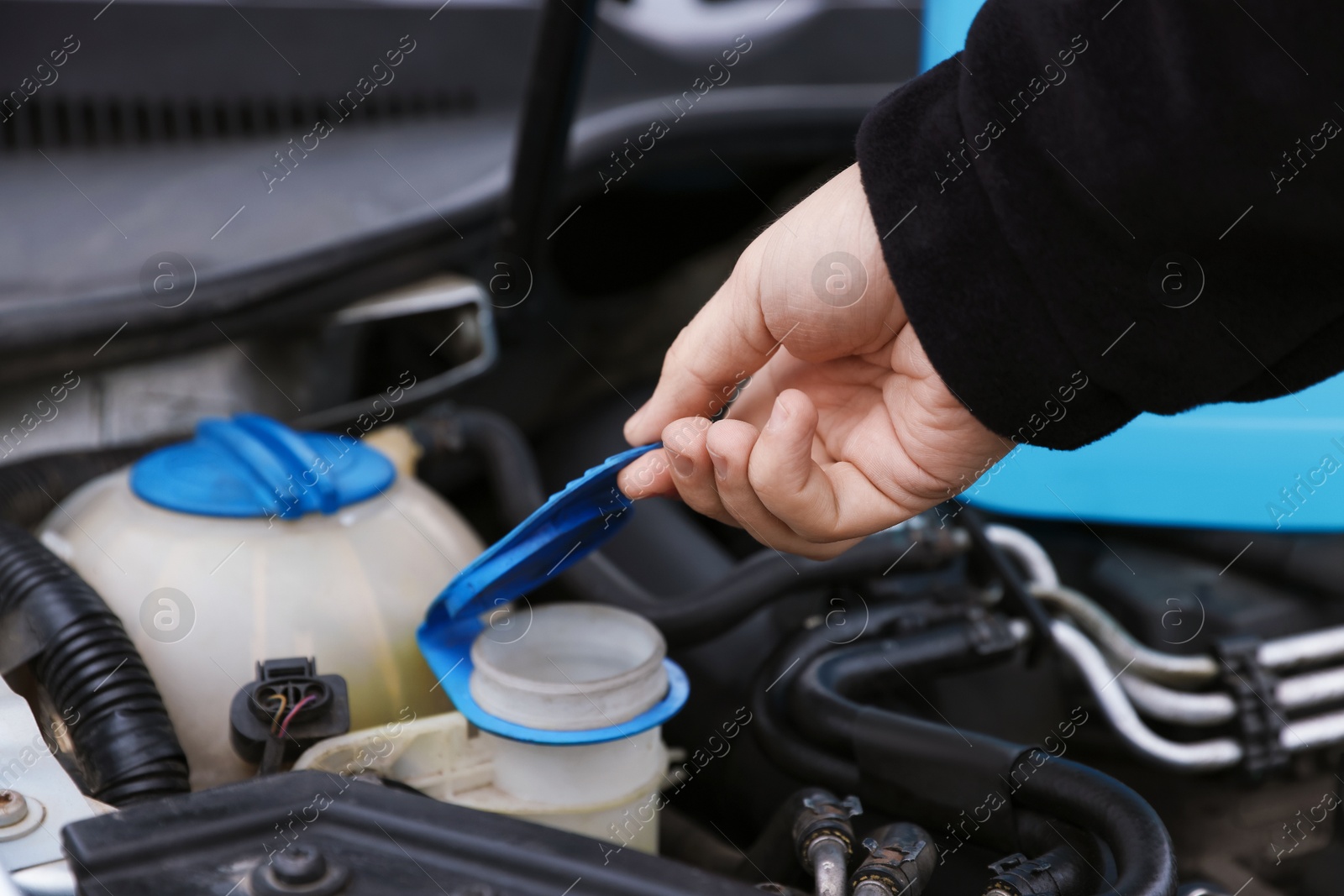 Photo of Man opening car windshield washer reservoir, closeup