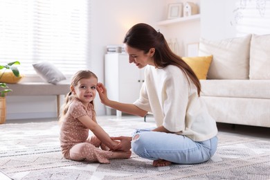 Photo of Happy mother with her cute little daughter on carpet at home