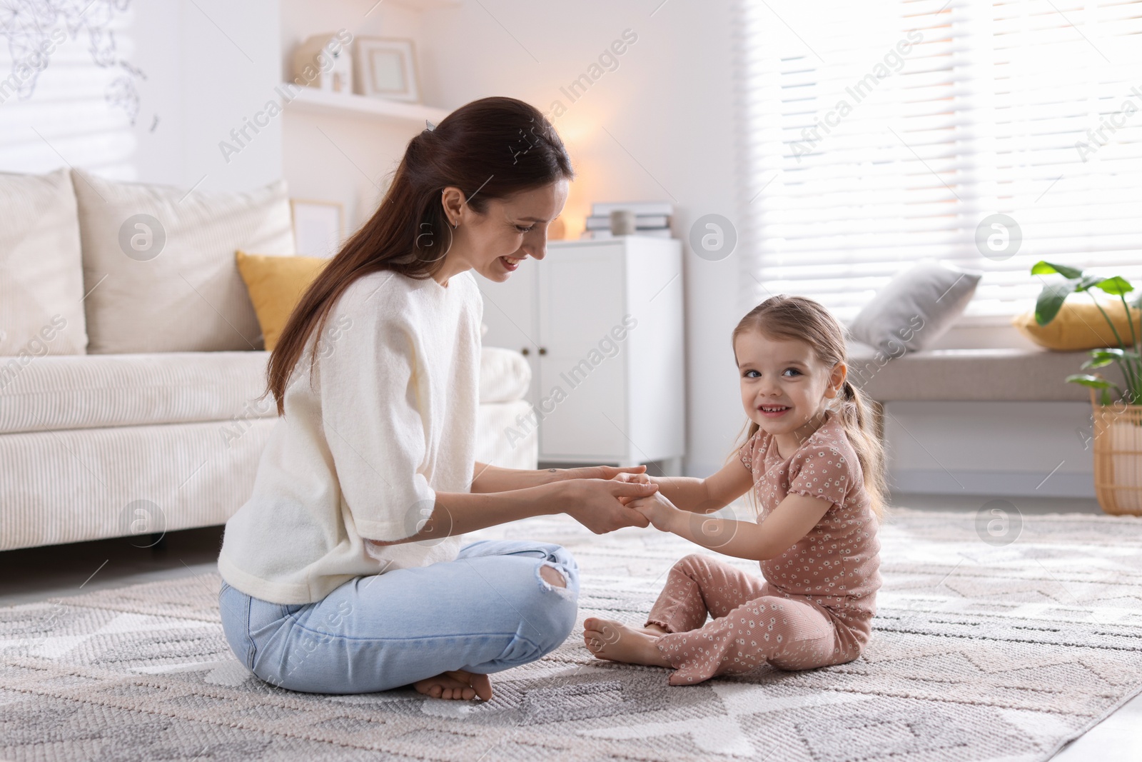 Photo of Happy mother with her cute little daughter on carpet at home