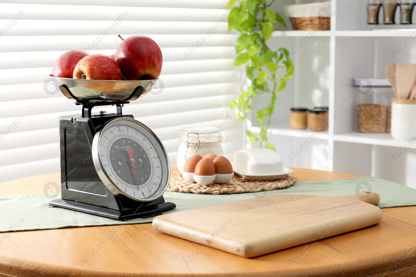 Photo of Retro mechanical kitchen scale, products and stationery on wooden table indoors