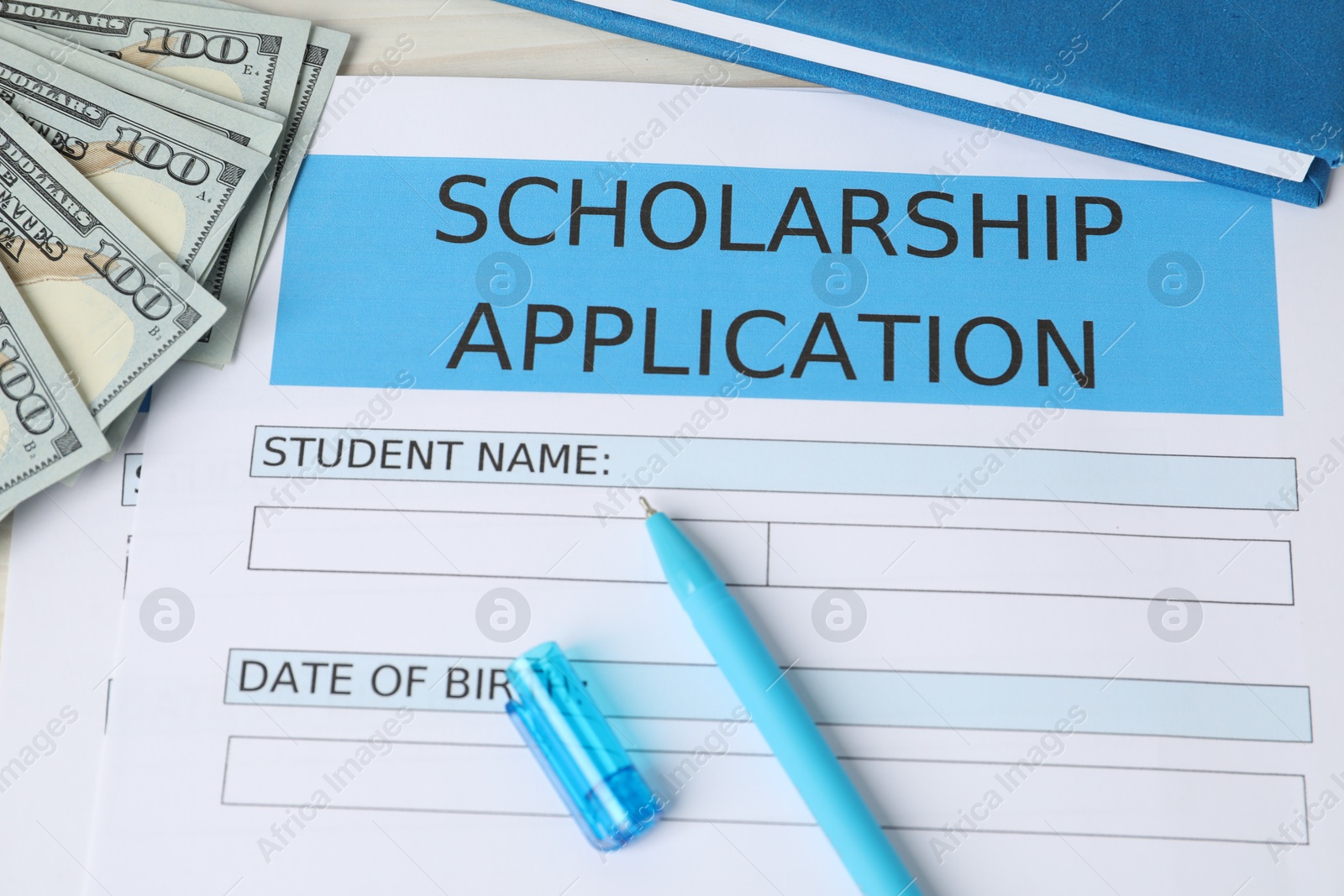 Photo of Scholarship application form, pen, dollar banknotes and book on table, above view