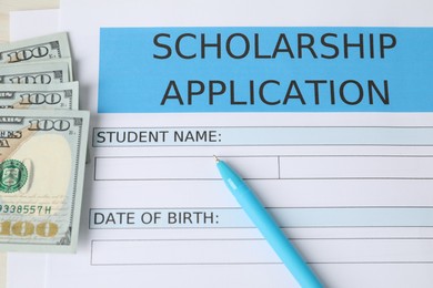 Scholarship application form, pen, dollar banknotes and book on table, top view