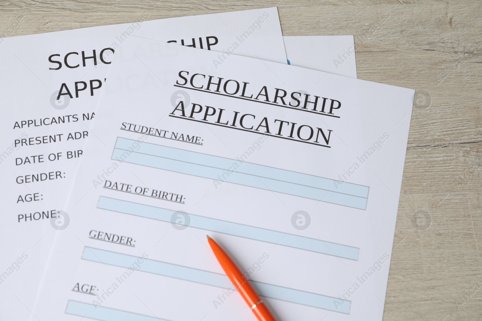 Photo of Scholarship application forms and pen on wooden table, above view