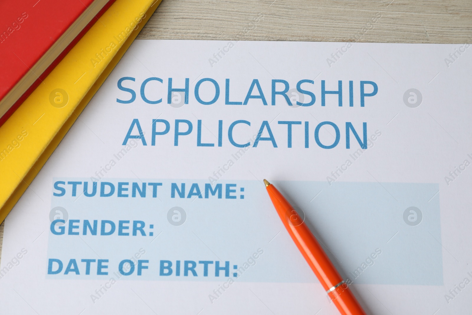 Photo of Scholarship application form, pen and books on wooden table, flat lay