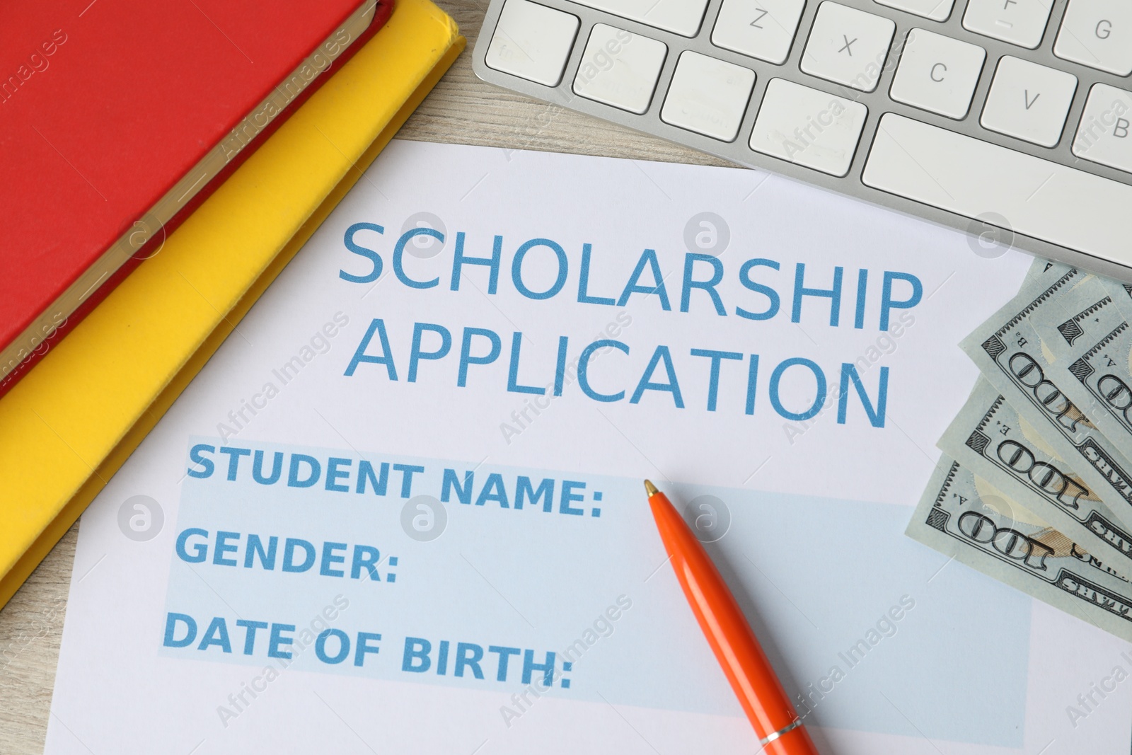 Photo of Scholarship application form, pen, dollar banknotes, computer keyboard and books on wooden table, flat lay