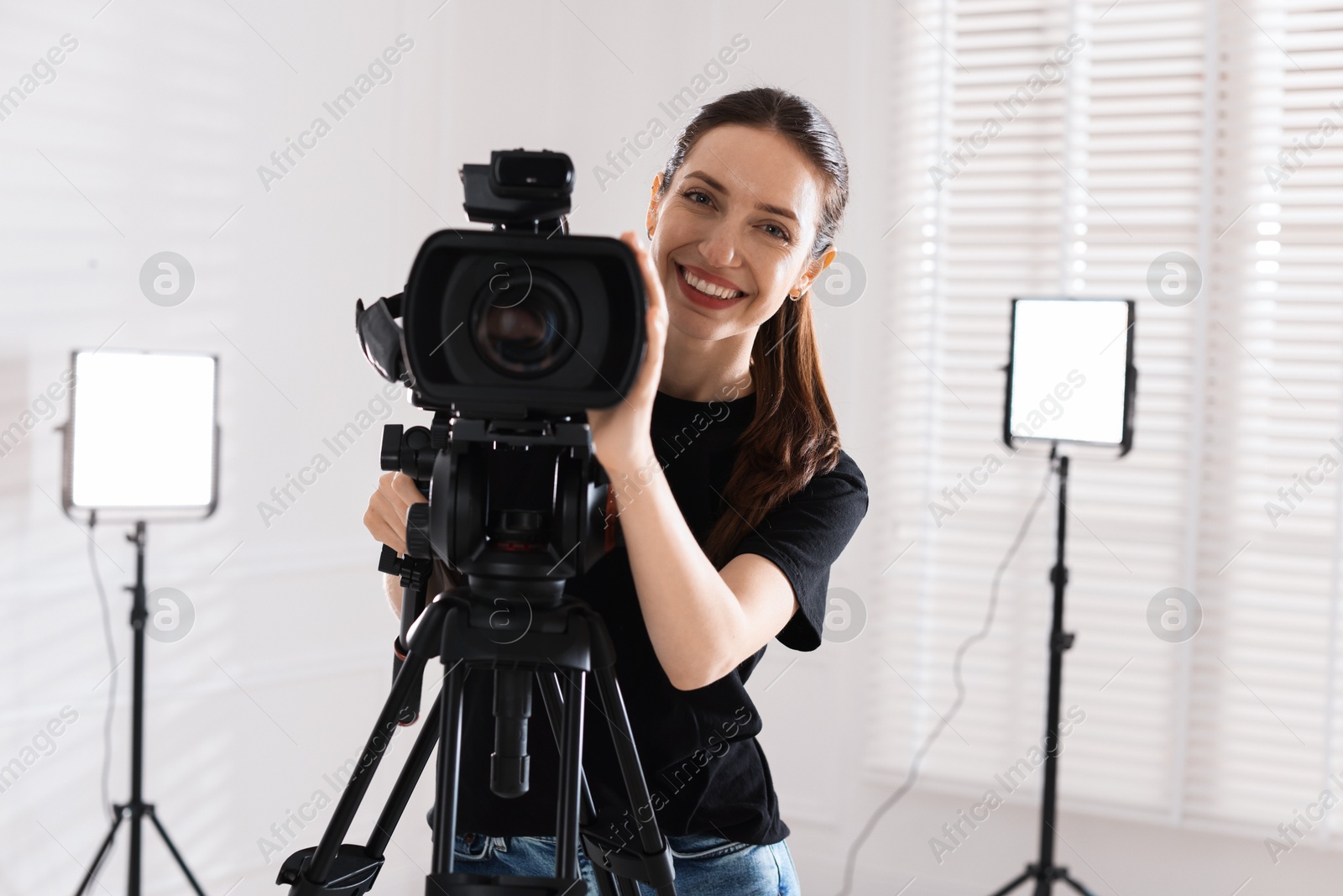 Photo of Happy woman with professional video camera in studio