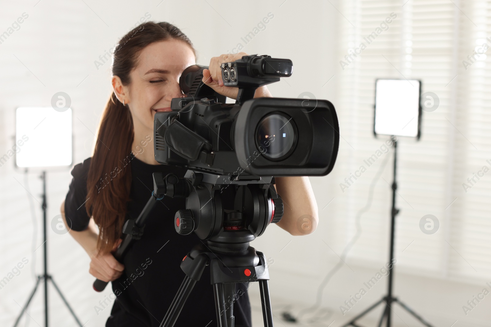 Photo of Happy woman with professional video camera in studio