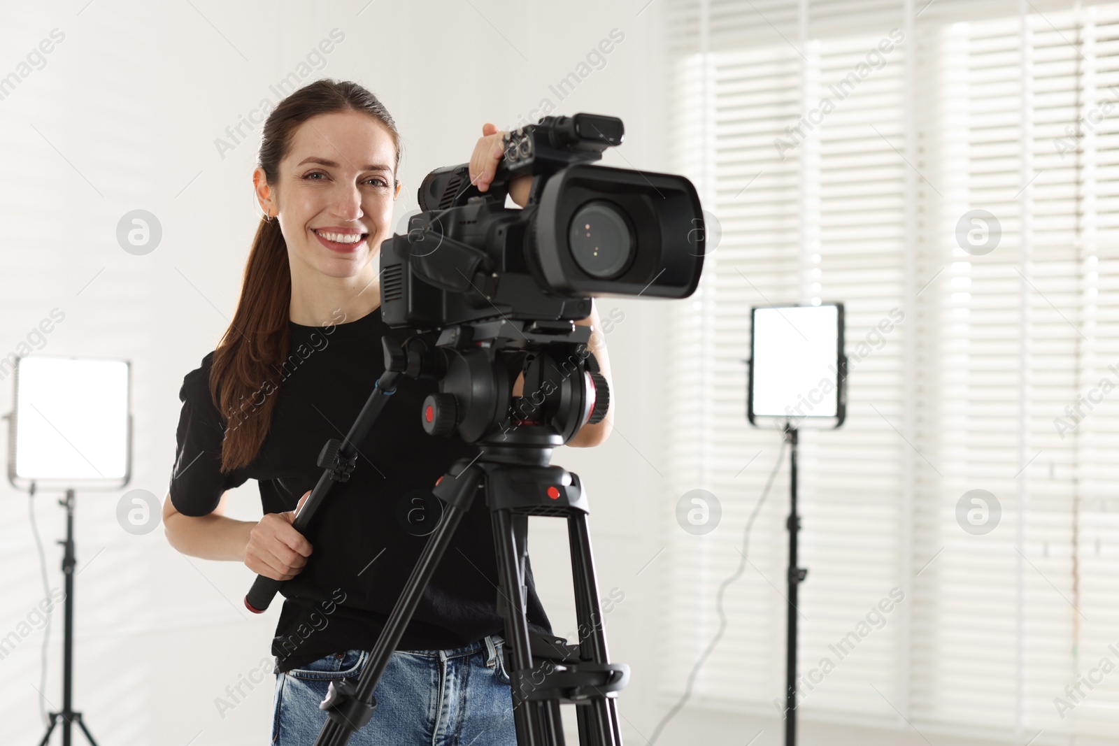 Photo of Happy woman with professional video camera in studio, space for text