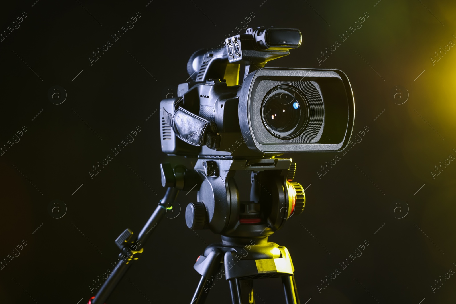 Photo of Modern video camera with tripod on black background, closeup