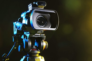 Photo of Modern video camera on black background, closeup. Space for text