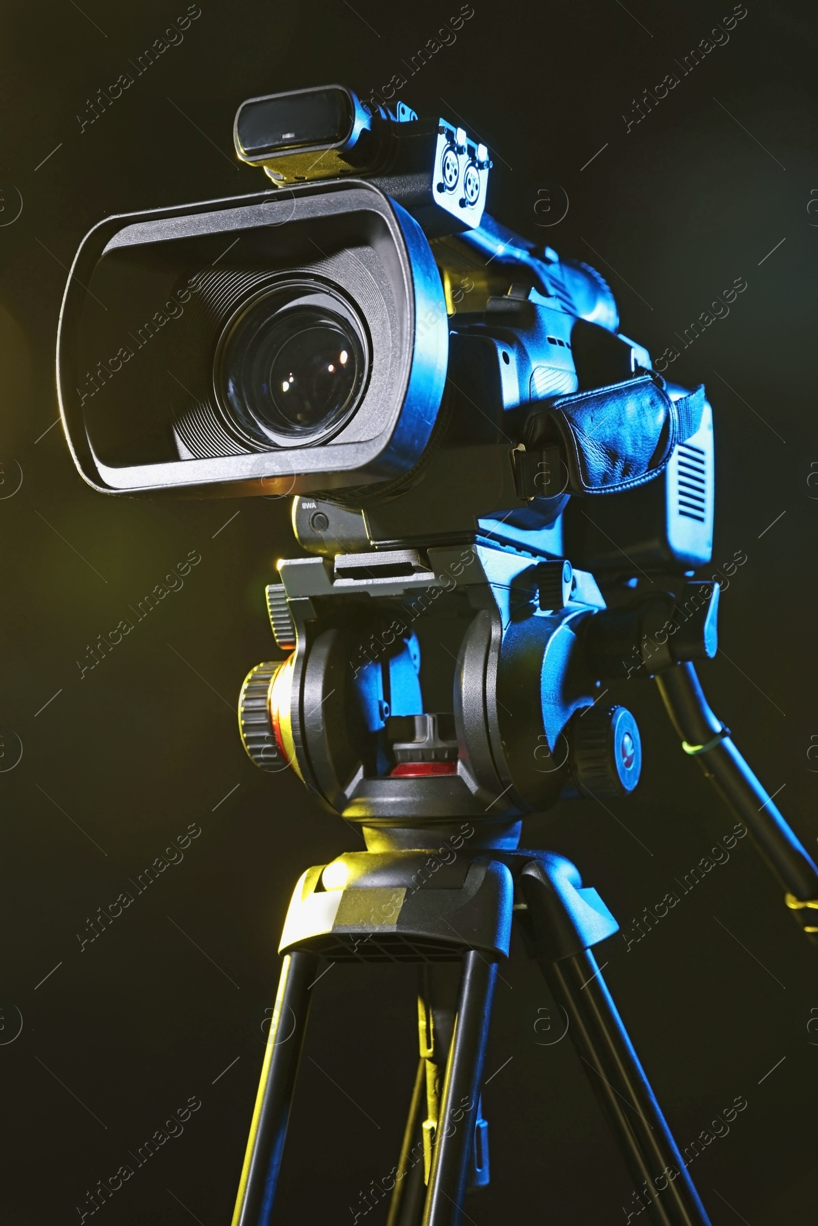 Photo of Modern video camera with tripod on black background, closeup